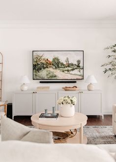 a living room filled with furniture and a painting on the wall above it's coffee table