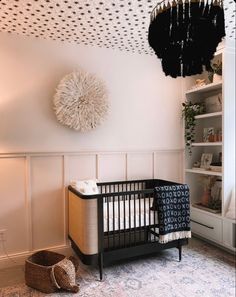 a baby crib in the corner of a room with a chandelier above it