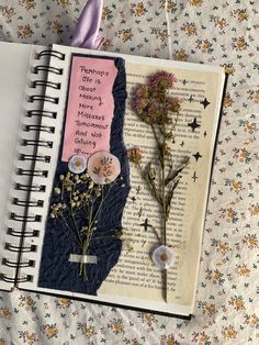 an open book with flowers on it sitting next to a pair of scissors and thread