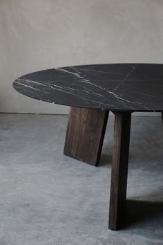 a black marble table sitting on top of a cement floor next to a white wall