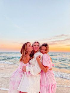 three women hugging each other on the beach