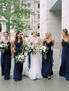 a group of women standing next to each other in front of a building with bouquets