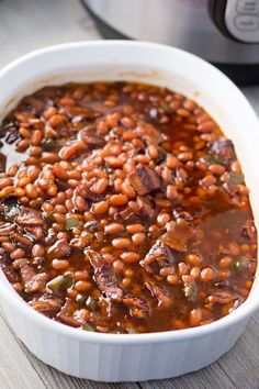 a white bowl filled with beans and meat next to an instant pressure cooker in the background