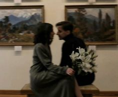 a man and woman kissing in front of paintings