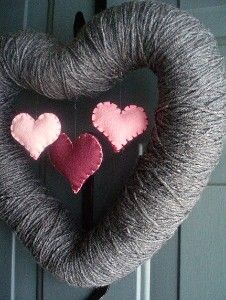 a yarn wreath with two hearts hanging from it's side on the front door