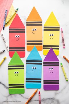 colorful crayons with faces drawn on them and colored pencils next to them