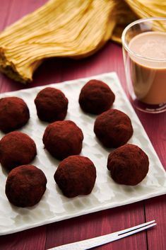 chocolate truffles on a plate next to a cup of coffee