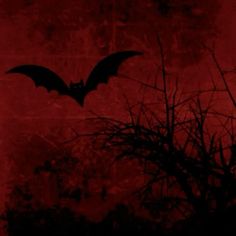 a bat flying in the sky over some trees and branches with red light coming from behind it