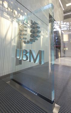 a glass sign that reads u b m in front of a building's entrance