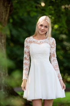 a woman in a short white dress posing for the camera with her hands on her hips