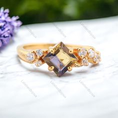 a gold ring with an amethorate and white diamonds on the side, next to purple flowers