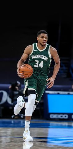 a basketball player dribbling the ball down the court with one foot on his hip