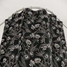 a black and white floral curtain hanging from a metal rod