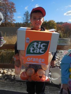 two children in costumes holding oranges and an orange juice box with the caption, it's halloween