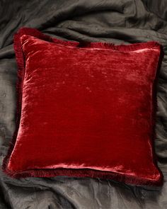 a red velvet pillow sitting on top of a bed