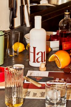 an assortment of liquors and glasses on a counter with oranges in the background