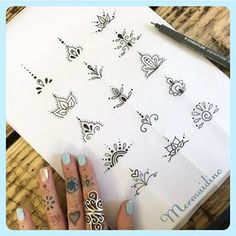 a woman's hand with some tattoos on her fingers and fingernails next to a piece of paper