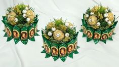 three green and gold christmas decorations sitting on top of a white cloth covered tablecloth