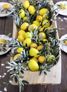 a bunch of lemons sitting on top of a wooden table next to white plates