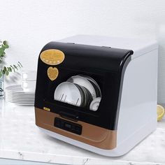 a white and black toaster sitting on top of a counter next to some plates