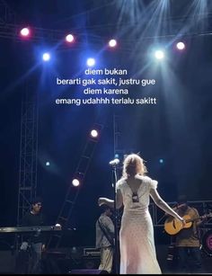 a woman standing on top of a stage holding a guitar