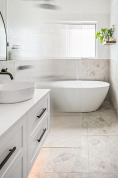 a bathroom with a large white bathtub next to a sink and a mirror on the wall