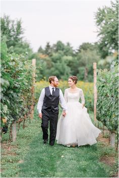 a bride and groom walking through the vineyard