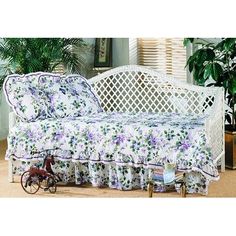 a white daybed with floral print on it and a toy bike in the foreground