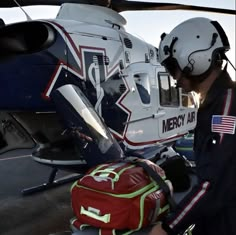 a man in uniform standing next to a helicopter with an american flag backpack on it