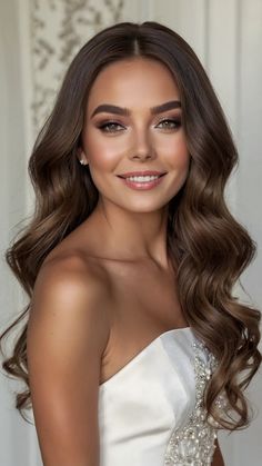 a woman with long hair wearing a strapless white dress and smiling at the camera