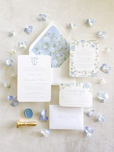 the wedding stationery is laid out with blue flowers