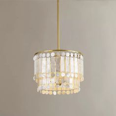 a chandelier hanging from the ceiling with white and gold circles on it's sides