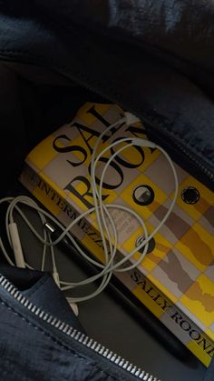 a yellow and white book with ear buds in it's pocket next to headphones