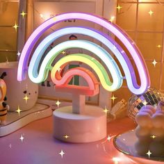 a colorful light sculpture on top of a table next to a plate with donuts