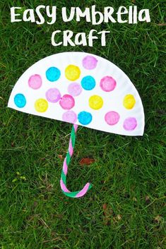 an umbrella made out of paper with the words easy umbrella craft on it in front of green grass