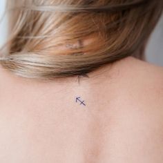 the back of a woman's neck with an arrow tattoo on her left shoulder