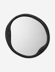 an oval mirror with black frame on a white wall