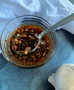 a glass jar filled with food sitting on top of a blue towel next to a garlic clove