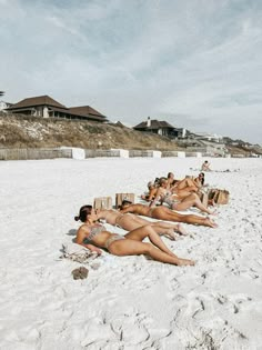 several women laying on the beach in bikinis