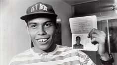 a black and white photo of a baseball player holding up a card with an image of a man on it