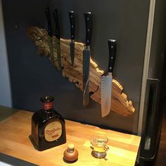 there is a bottle and knife on the counter next to some knives that are hanging on the wall