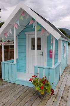 a small blue and white house on a wooden deck