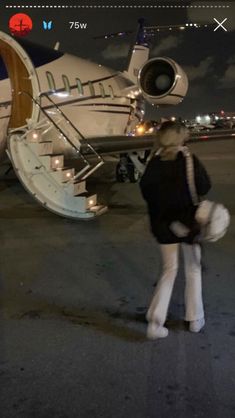 a woman standing in front of an airplane at night