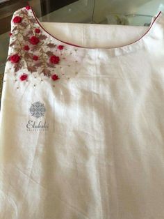 a white shirt with red flowers on the front and back, sitting on a table