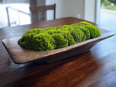 a moss covered dish sitting on top of a wooden table