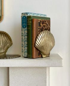 two books are sitting on a shelf next to a bookend with a gold shell