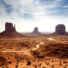 an aerial view of the desert with mountains in the distance and clouds in the sky