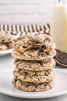 a stack of cookies sitting on top of a white plate next to a glass of milk