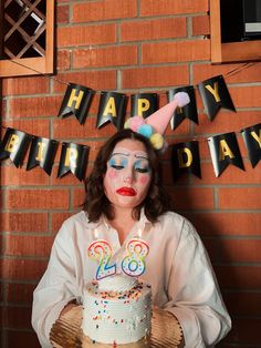 a woman in clown makeup holding a birthday cake