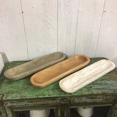 three wooden spoons sitting on top of an old green cabinet next to two white vases